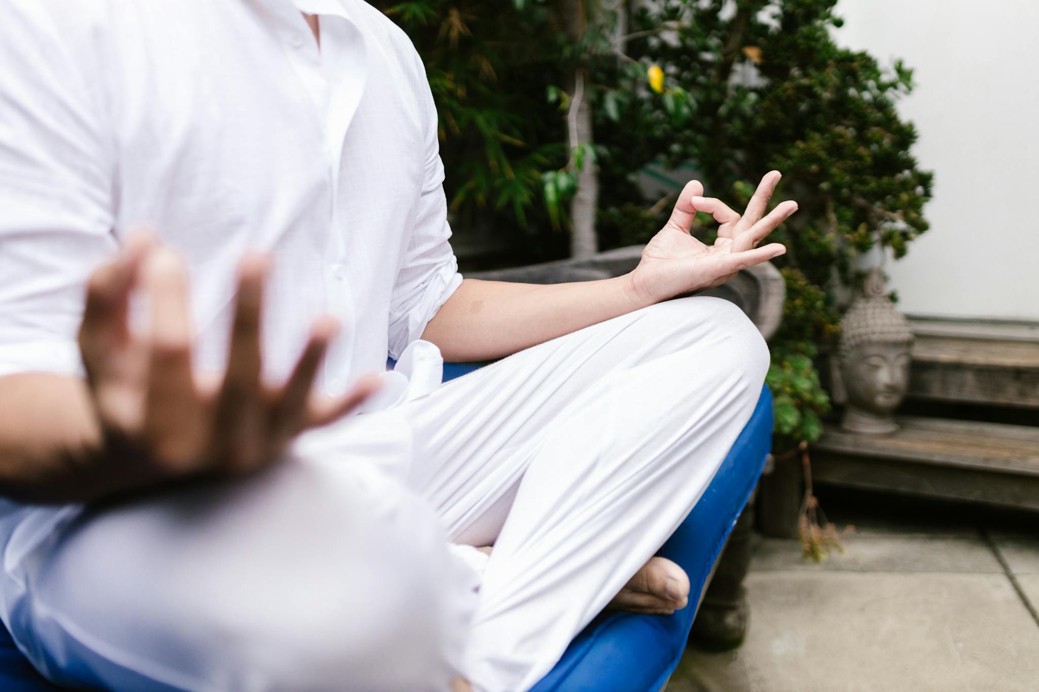 A person in white practicing yoga meditation outdoors in a serene environment.