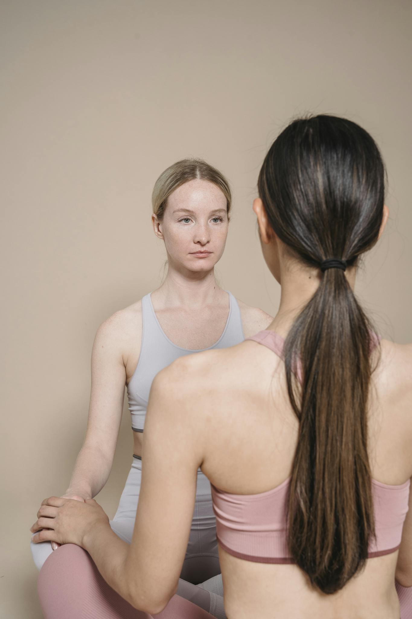 Two women practicing meditation indoors, sitting in a calm environment.